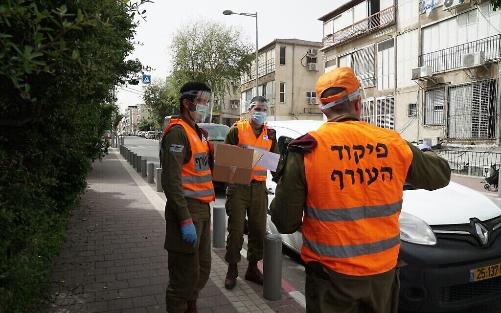 Des soldats israéliens donnent de la nourriture aux habitants de la ville de Bnei Brak dans le centre d'Israël. La ville a été largement coupée du reste du pays à cause de l'épidémie de coronavirus, le 5 avril 2020. (Crédit : Armée israélienne)