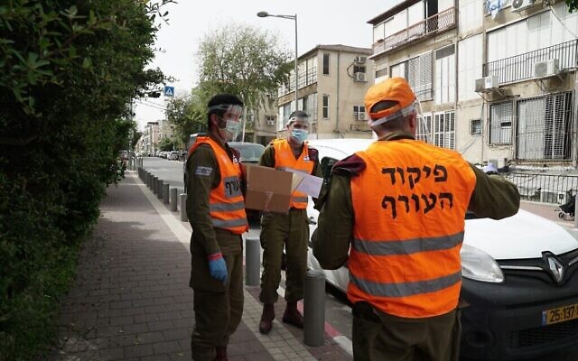 Des soldats israéliens donnent de la nourriture aux habitants de la ville de Bnei Brak dans le centre d'Israël. La ville a été largement coupée du reste du pays à cause de l'épidémie de coronavirus, le 5 avril 2020. (Crédit : Armée israélienne)