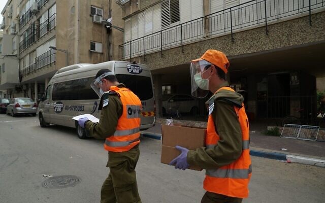 Des soldats israéliens donnent de la nourriture aux habitants de Bnei Brak, dans le centre d'Israël. La ville a été largement coupée du reste du pays à cause de l'épidémie de coronavirus, le 5 avril 2020. (Crédit : Armée israélienne)