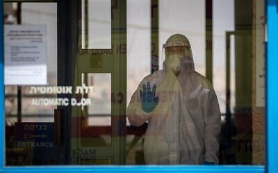 Un urgentiste du Magen David Adom, portant un équipement de protection, arrive pour tester au COVID-19 des résidents dans la maison de retraite Nofim le 27 mars 2020. (Yonatan Sindel / Flash90)