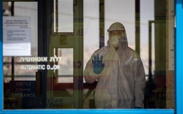 Un urgentiste du Magen David Adom, portant un équipement de protection, arrive pour tester au COVID-19 des résidents dans la maison de retraite Nofim le 27 mars 2020. (Yonatan Sindel / Flash90)