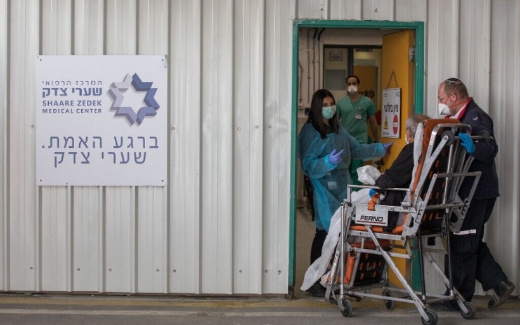Des personnels du Magen David Adom et hospitaliers transportent un malade du coronavirus présumé à l'hôpital Shaare Zedek de Jérusalem, le 31 mars 2020 (Crédit : Nati Shohat /FLASH90) Des personnels du Magen David Adom et hospitaliers transportent un malade du coronavirus présumé à l'hôpital Shaare Zedek de Jérusalem, le 31 mars 2020 (Crédit : Nati Shohat /FLASH90)