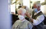 Un coiffeur porte un masque, tout comme son client, à Dortmund, le 
mai 2020. (Crédit : Ina FASSBENDER / AFP)