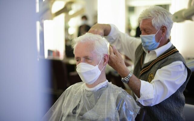 Un coiffeur porte un masque, tout comme son client, à Dortmund, le 
mai 2020. (Crédit : Ina FASSBENDER / AFP)