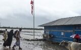 Des résidents passent à côté d'un drapeau signalant un grand danger avant l'arrivée prévue du cyclone Amphan, à Dacope dans la région de Khulna, le 20 mai 2020. (Photo par Munir uz Zaman / AFP)