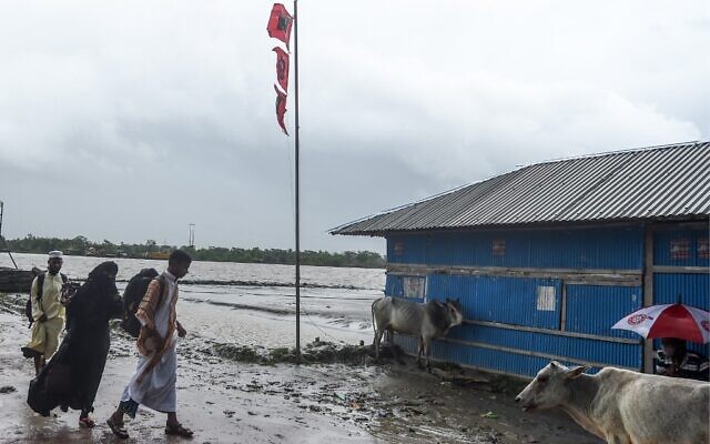 Des résidents passent à côté d'un drapeau signalant un grand danger avant l'arrivée prévue du cyclone Amphan, à Dacope dans la région de Khulna, le 20 mai 2020. (Photo par Munir uz Zaman / AFP) Des résidents passent à côté d'un drapeau signalant un grand danger avant l'arrivée prévue du cyclone Amphan, à Dacope dans la région de Khulna, le 20 mai 2020. (Photo par Munir uz Zaman / AFP)