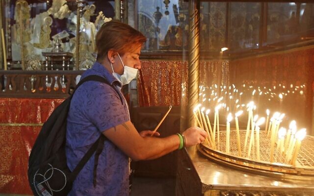 Un fidèle chrétien allume des bougies dans l'église de la Nativité de Bethléem après sa réouverture, le 26 mai 2020. (Crédit : Musa Al SHAER / AFP)