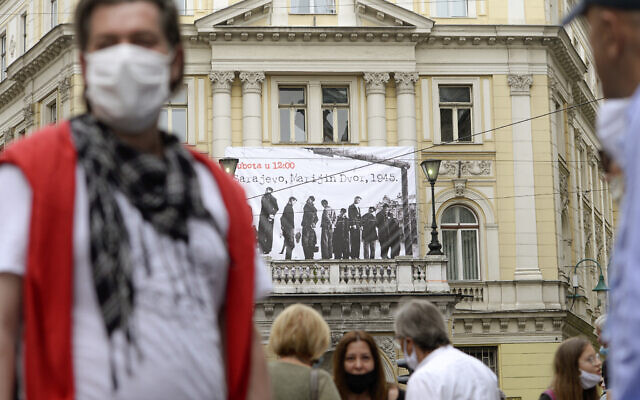 Des gens devant une bannière montrant des victimes exécutées par pendaison en 1945 par le régime croate pro-nazi oustachi pendant la Seconde Guerre mondiale, à Sarajevo, en Bosnie, le 16 mai 2020. (Crédit : AP / Kemal Softic) Des gens devant une bannière montrant des victimes exécutées par pendaison en 1945 par le régime croate pro-nazi oustachi pendant la Seconde Guerre mondiale, à Sarajevo, en Bosnie, le 16 mai 2020. (Crédit : AP / Kemal Softic)