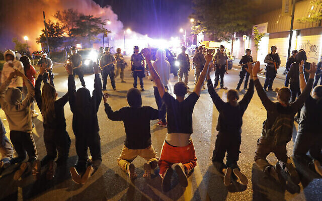 Des manifestants s'agenouillent devant la police, le 30 mai 2020, à Minneapolis. (Crédit : AP Photo / Julio Cortez) Des manifestants s'agenouillent devant la police, le 30 mai 2020, à Minneapolis. (Crédit : AP Photo / Julio Cortez)