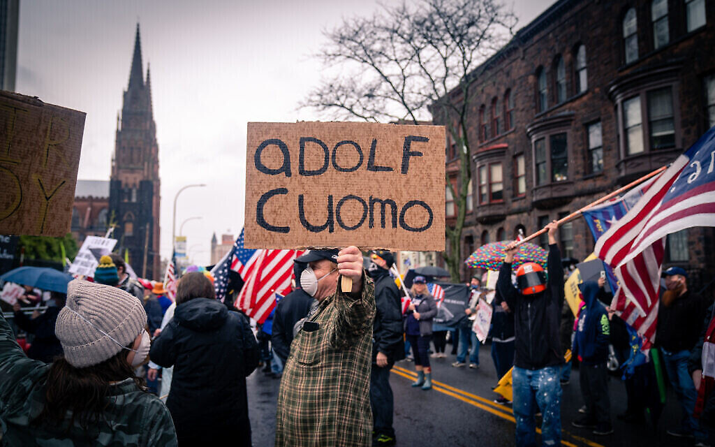 Un manifestant anti-confinement compare le gouverneur de New York Andrew Cuomo à Adolf Hitler lors d'une manifestation devant la résidence du gouverneur dans la capitale de l'État d'Albany, New York, le 1er mai 2020. (Crédit : Luke Tress/Times of Israël)