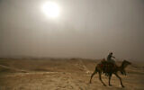 Un Arabe monte son chameau dans la brume aux alentours de la mosquée Nebi Musa, près de la ville de Jéricho, en Cisjordanie, lors d'une vague de chaleur, le 4 mai 2009. (AP Photo/Dan Balilty)
