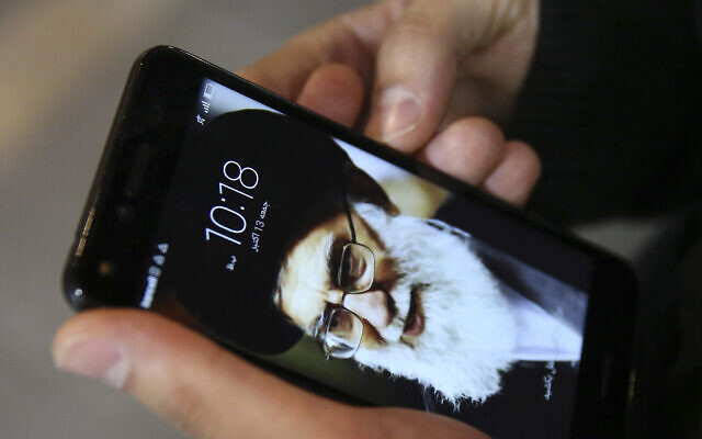 Un résident de Téhéran, Hamed Ghassemi, regarde son téléphone portable, avec un portrait du Guide suprême iranien, l'Ayatollah Ali Khamenei. (AP Photo/Vahid Salemi)