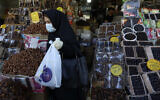 Une femme portant un masque et des gants pour empêcher la propagation du coronavirus fait ses courses pendant le mois sacré du Ramadan à Téhéran, le 27 avril 2020 (Crédit : AP Photo/Vahid Salemi)
