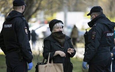 Des policiers russes, portant des masques faciaux pour se protéger du coronavirus, parlent à une femme alors qu'ils vérifient ses documents pour s'assurer qu'elle est bien auto-quarantaine en raison du coronavirus, à Moscou, en Russie, le 28 avril 2020. (AP Photo/Alexander Zemlianichenko)