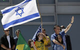 Le président brésilien Jair Bolsonaro, à droite, étreint sa fille alors que des partisans brandissent des drapeaux israélien, brésilien et américain au cours d'une manifestation contre son ex-ministre de la Justice Sergio Moro et contre la Cour suprême devant le palais présidentiel Planalto, à Brasilia, au Brésil, le 3 mai 2020 (Crédit : AP Photo/Eraldo Peres)
