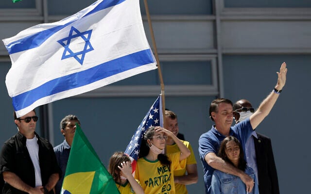 Le président brésilien Jair Bolsonaro, à droite, étreint sa fille alors que des partisans brandissent des drapeaux israélien, brésilien et américain au cours d'une manifestation contre son ex-ministre de la Justice Sergio Moro et contre la Cour suprême devant le palais présidentiel Planalto, à Brasilia, au Brésil, le 3 mai 2020 (Crédit : AP Photo/Eraldo Peres) Le président brésilien Jair Bolsonaro, à droite, étreint sa fille alors que des partisans brandissent des drapeaux israélien, brésilien et américain au cours d'une manifestation contre son ex-ministre de la Justice Sergio Moro et contre la Cour suprême devant le palais présidentiel Planalto, à Brasilia, au Brésil, le 3 mai 2020 (Crédit : AP Photo/Eraldo Peres)