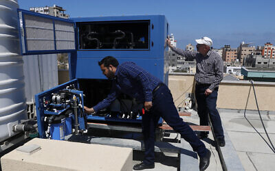 L’ingénieur palestinien Raed Nakhal du Palestine Children's Relief Fund, à droite, et l'ingénieur Abdullah Dewik, vérifiant la machine GEN-M qui génère de l'eau potable à l'hôpital pédiatrique al-Rantisi à Gaza, le 30 avril 2020. (Crédit : Adel Hana/AP)