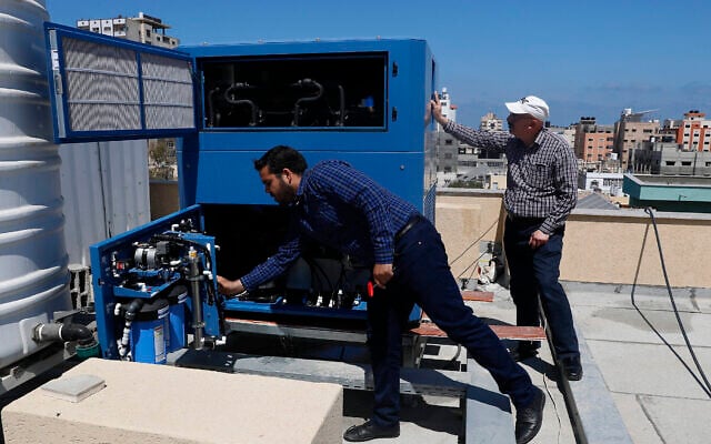 L’ingénieur palestinien Raed Nakhal du Palestine Children's Relief Fund, à droite, et l'ingénieur Abdullah Dewik, vérifiant la machine GEN-M qui génère de l'eau potable à l'hôpital pédiatrique al-Rantisi à Gaza, le 30 avril 2020. (Crédit : Adel Hana/AP)