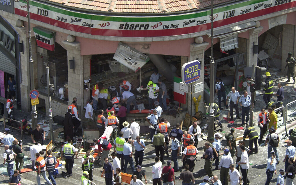 La police et les secouristes entourant la scène d'un attentat-suicide à l'intérieur de la pizzeria Sbarro, à Jérusalem, le 9 août 2001. Quinze personnes ont été tuées et 130 blessées. Une seizième victime est décédée en 2023. (Crédit : Peter Dejong/AP)