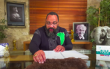 Dieudonné M'Bala M'Bala, dans une vidéo mettant en scène Simone Veil et le négationniste Robert Faurisson, devant des portraits de ce dernier et du maréchal Pétain. (Crédit : Capture d’écran YouTube/Dieudonné Officiel)