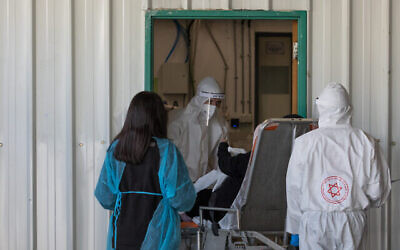 Des employés de Magen David Adom en équipement de protection devant l'hôpital Shaare Zedek à Jérusalem, le 30 avril 2020. (Crédit : Nati Shohat/Flash90)