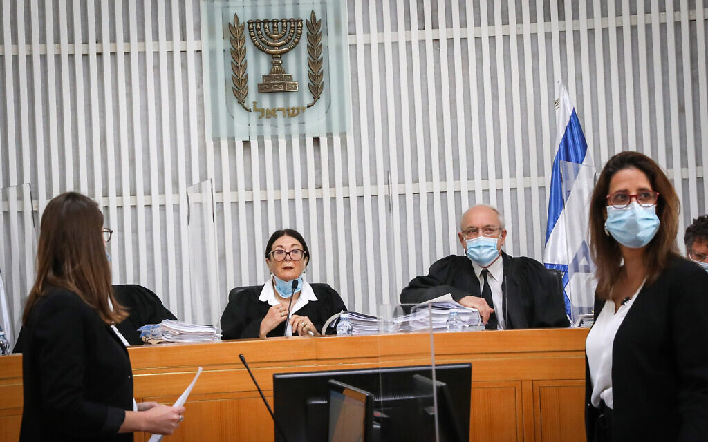 La présidente de la Cour suprême Esther Hayut (au centre) et d'autres juges, portant des masques et avec des séparateurs en plastique transparent entre eux, tiennent une audience pour savoir si Benjamin Netanyahu est éligible pour former le prochain gouvernement d'Israël alors qu'il est mis en accusation, le 3 mai 2020. (Crédit : Yossi Zamir/POOL)