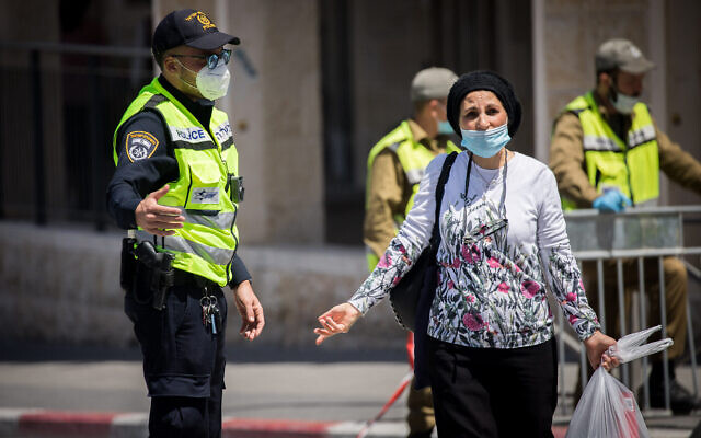 Une femme discute avec un policier à un barrage routier dans le quartier de Romema à Jérusalem, qui est en quarantaine pour empêcher la propagation du coronavirus, le 4 mai 2020. (Yonatan Sindel/Flash90) Une femme discute avec un policier à un barrage routier dans le quartier de Romema à Jérusalem, qui est en quarantaine pour empêcher la propagation du coronavirus, le 4 mai 2020. (Yonatan Sindel/Flash90)