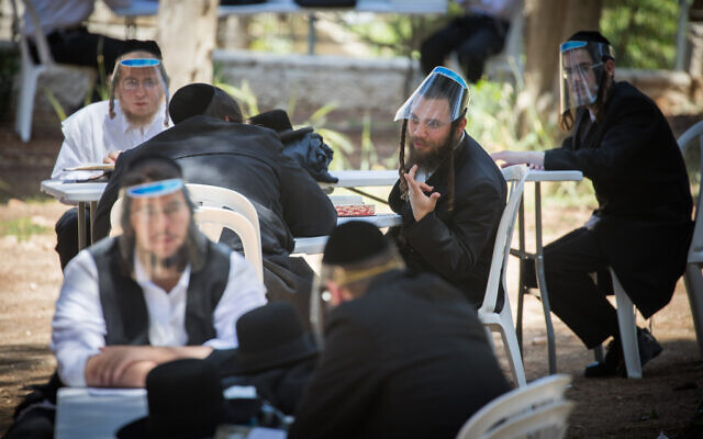 Des hommes ultra-orthodoxes portent des visières de protection comme mesure prise contre le coronavirus, lors d'une étude en plein air à Jérusalem, le 4 mai 2020. (Crédit : Yonatan Sindel/Flash90)