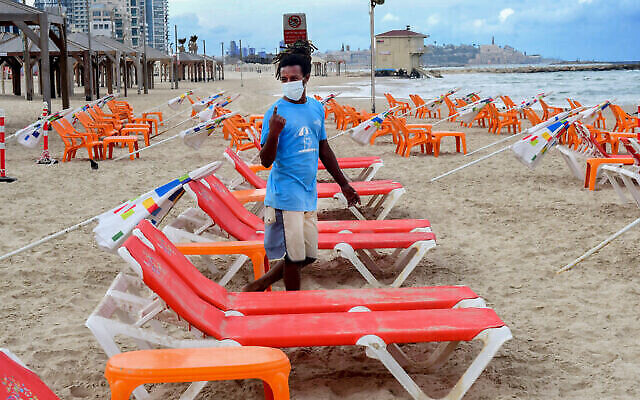 Des travailleurs installent des transats et des parasols sur la plage de Tel Aviv, le 5 mai 2020. (Avshalom Sassoni/Flash90) Des travailleurs installent des transats et des parasols sur la plage de Tel Aviv, le 5 mai 2020. (Avshalom Sassoni/Flash90)