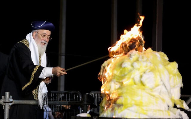 Le grand rabbin séfarade de Jérusalem, le rabbin Shlomo Amar, allume un feu de joie lors des célébrations de la fête juive de Lag BaOmer au mont Meron, dans le nord d'Israël, le 11 mai 2020. (David Cohen/Flash90)