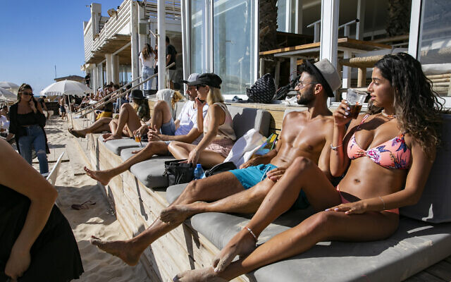 Des Israéliens se prélassent devant un restaurant fermé sur la plage de Tel Aviv, le 25 mai 2020, alors que les plages de Tel Aviv ont été officiellement rouvertes au public après leur fermeture afin de prévenir la propagation du coronavirus. (Olivier Fitoussi/Flash90)