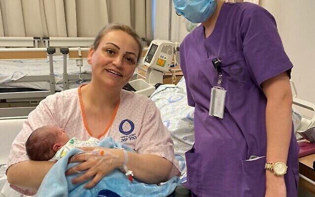 Après 7 ans de traitements pour des problèmes de fertilité et 48 heures de travail, Danit Shipe tient enfin dans ses bras son bébé, né le 72e anniversaire de l'Indépendance d'Israël, le 29 avril 2020. Elle est entourée de la sage-femme Katia Amarna. (Crédit : centre médical Hillel Yaffe)