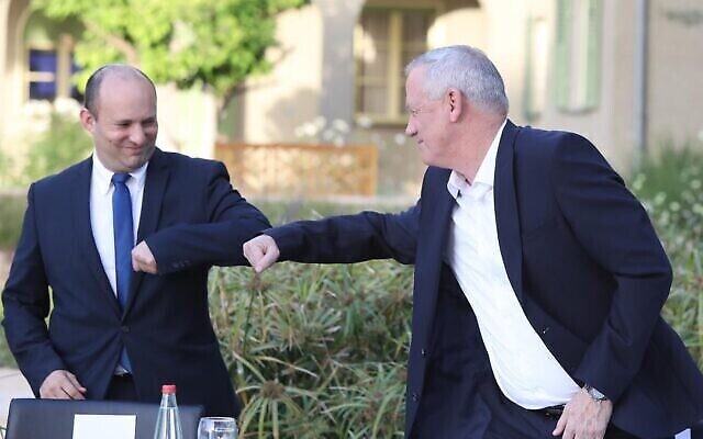 Le nouveau ministre de la Défense Benny Gantz (à droite) et le ministre de la Défense sortant Naftali Bennett se saluent avec leur coude lors de la cérémonie de passation des pouvoirs au ministère de la Défense à Tel Aviv, le 18 mai 2020. (Oded Karni/GPO)