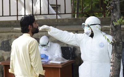 Un membre du personnel médical portant un équipement de protection individuelle (EPI) effectue un test sur un patient suspecté d’être porteur du coronavirus à l'hôpital afghano-japonais des maladies transmissibles de Kaboul, le 9 mai 2020. (Crédit : WAKIL KOHSAR / AFP)
