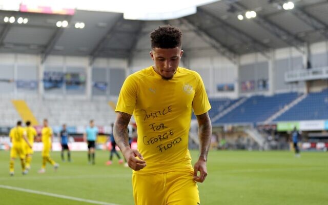 Le milieu de terrain anglais de Dortmund Jadon Sancho avec un t-shirt "Justice pour George Floyd" après avoir marqué le troisième but de son équipe lors du match de football de première division allemande opposant le Bundesliga SC Paderborn 07 au Borussia Dortmund au Benteler Arena de Paderborn, le 31 mai 2020. (Crédit : Lars Baron / AFP) Le milieu de terrain anglais de Dortmund Jadon Sancho avec un t-shirt "Justice pour George Floyd" après avoir marqué le troisième but de son équipe lors du match de football de première division allemande opposant le Bundesliga SC Paderborn 07 au Borussia Dortmund au Benteler Arena de Paderborn, le 31 mai 2020. (Crédit : Lars Baron / AFP)
