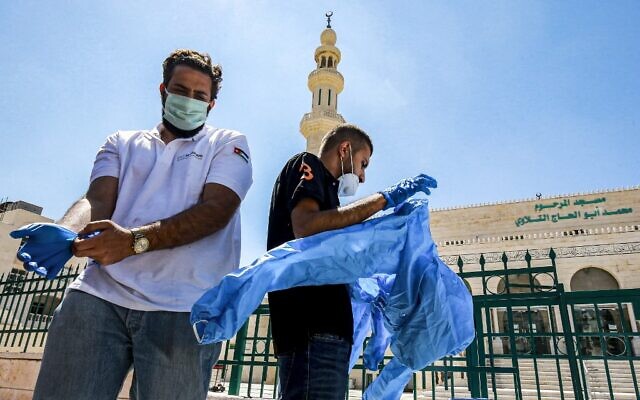 Des travailleurs portent un équipement de protection individuelle avant de stériliser une mosquée à Amman, la capitale de la Jordanie, le 3 juin 2020, avant sa réouverture. (Crédit : Khalil MAZRAAWI / AFP) Des travailleurs portent un équipement de protection individuelle avant de stériliser une mosquée à Amman, la capitale de la Jordanie, le 3 juin 2020, avant sa réouverture. (Crédit : Khalil MAZRAAWI / AFP)
