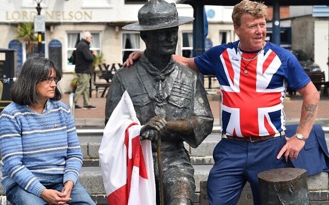 Steve Dorris, un résident local, portant un t-shirt avec le drapeau de l'Union, pose avec une statue de Robert Baden-Powell, le fondateur du mouvement scout, sur le quai de Bournemouth, dans le sud de l'Angleterre, le 11 juin 2020, après le conseil a annoncé qu'il retirerait la statue. (Crédit : Glyn KIRK / AFP)