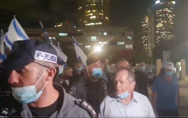 Capture d'écran d'une vidéo montrant le journaliste et commentateur Amnon Abramovich, au centre, escorté par la police après avoir été menacé par une foule lors d'une manifestation de droite à Tel Aviv, le 20 juin 2020. (Crédit : Twitter) Capture d'écran d'une vidéo montrant le journaliste et commentateur Amnon Abramovich, au centre, escorté par la police après avoir été menacé par une foule lors d'une manifestation de droite à Tel Aviv, le 20 juin 2020. (Crédit : Twitter)