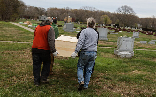 Le personnel du cimetière du Washington Memorial Park porte un cercueil pour l'inhumer, le 15 mai 2020. (Photo par Jonathan Alpeyrie/Polaris Images)