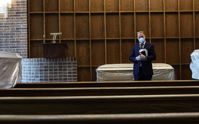 Le rabbin Greg Ackerman se tient à côté d'un défunt dans la chapelle du maison funéraire Gutterman, le 15 mai 2020, à Woodbury, New York. (Photo par Jonathan Alpeyrie/Polaris Images)