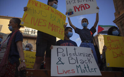 Des manifestants brandissent des pancartes pendant une manifestation à Jaffa contre la police israélienne après la mort d'un Palestinien autiste Iyad Halak, abattu par des policiers qui ont dit penser qu'il était armé, le 31 mai 2020. (Crédit : AP Photo/Oded Balilty)