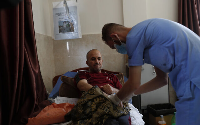 Un infirmier palestinien s'occupe de Jehad al-Qedra, atteint par un cancer, alors qu'il reçoit son traitement dans un hôpital du camp de réfugiés de Khan Younès, dans la bande de Gaza, le 16 juin 2020 (Crédit : AP Photo/Adel Hana)