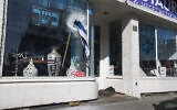 Une vitrine brisée et une pierre sur le trottoir alors qu'un drapeau israélien flotte sur la devanture du restaurant casher HaCarmel à Amsterdam, Pays-Bas, le 8 mai 2020, après qu'un homme a brisé la vitre. Le propriétaire, David Bar-On, a déclaré que son restaurant a été vandalisé pour la sixième fois dans ce qui semble être une nouvelle attaque antisémite. (AP Photo/Peter Dejong)