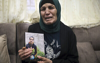 Rana, la mère d'Iyad Halak, 32 ans, brandit une photo de son fils au domicile familial de Wadi Joz, à Jérusalem-Est, le 30 mai 2020 (Crédit : AP Photo/Mahmoud Illean)