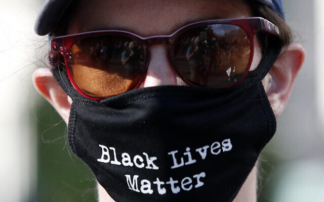 Un manifestant porte un masque facial lors d'une manifestation pour la mort de George Floyd, le dimanche 31 mai 2020, près de la Maison Blanche à Washington. Floyd est mort après avoir été immobilisé par des officiers de police de Minneapolis. (AP Photo/Alex Brandon)