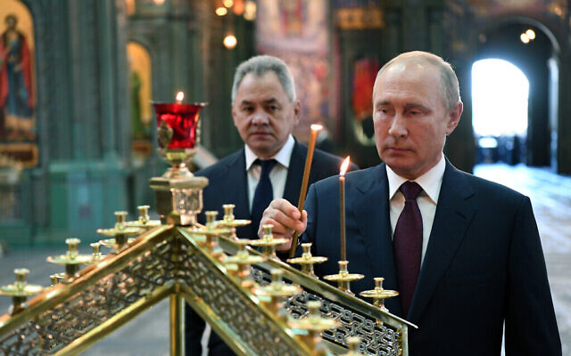 Le président russe Vladimir Poutine, à droite, allume une bougie avec le ministre russe de la Défense Sergei Shoigu en arrière-plan, à la cathédrale des forces armées russes, le 22 juin 2020. (Crédit : Alexei Nikolsky, Spoutnik, Kremlin Pool Photo via AP)