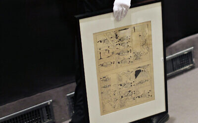 Un employé tient un dessin original encré et peint à l'eau de l'album de Tintin « Le Sceptre d'Ottokar » publié en 1938, dessiné par l’artiste belge Hergé, lors de la vente aux enchères de souvenirs rares de Tintin, à la maison de vente aux enchères de Drouot, à Paris, le 29 mai 2010. (Crédit : AP / Thibault Camus)