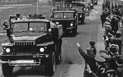 Des résidents applaudissent et saluent tandis qu'une colonne de véhicules armés transportant d'anciennes troupes soviétiques quitte Vilnius, le 3 mars 1992. (Crédit : Mendaugus Kublis / AP)