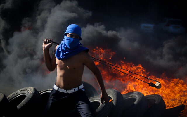 Photo d'illustration : Des manifestants palestiniens utilisent des frondes pour jeter des pierres aux soldats israéliens au cours d'affrontements à proximité de l'implantation de Beit El, le 13 novembre 2015 (Crédit : FLASH90)