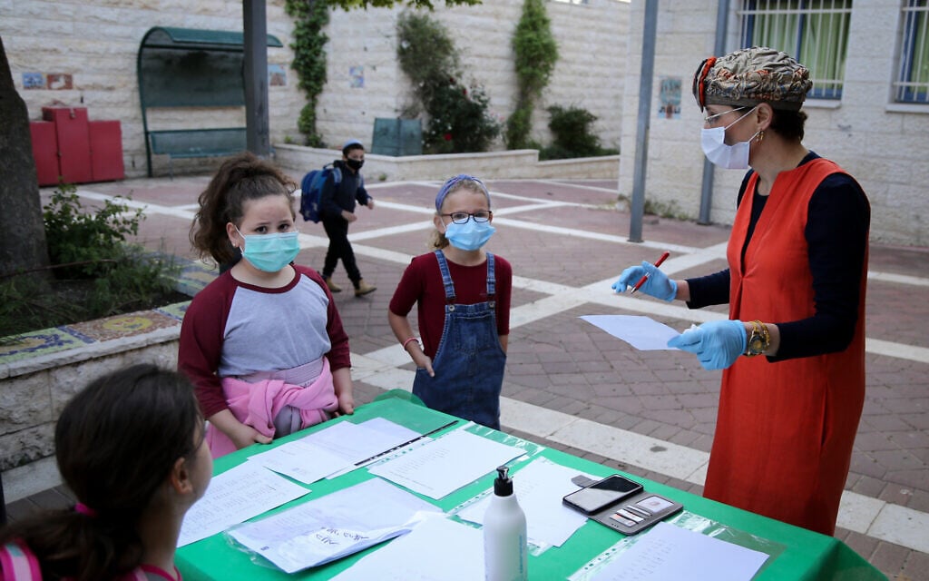 Les élèves israéliens doivent porter des masques et envoyer ou donner des documents signés, chaque matin, dans les écoles, pour garantir qu'ils sont en bonne santé dans un contexte de crise du coronavirus en 2020 (Crédit : Gershon Elinon/Flash90)